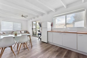 Una cocina moderna con armarios blancos, encimera de madera y un amplio ventanal.