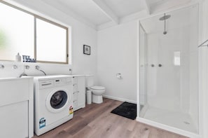 Mega convenient internal laundry station featuring a front-loading washing machine, deep sink, toilet, and an additional walk-in shower. - The Family Haven Sea Villas - Studio 1 & 2 (Rye)