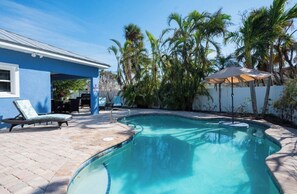A swimming pool with lounge chairs, a covered patio, and palm trees. - Exceptional Newer Beach Villa with Private Heated Pool! (Holmes Beach)