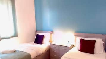 Ein Hotelzimmer mit zwei Betten, einem Nachttisch und einem Fenster mit Vorhängen.