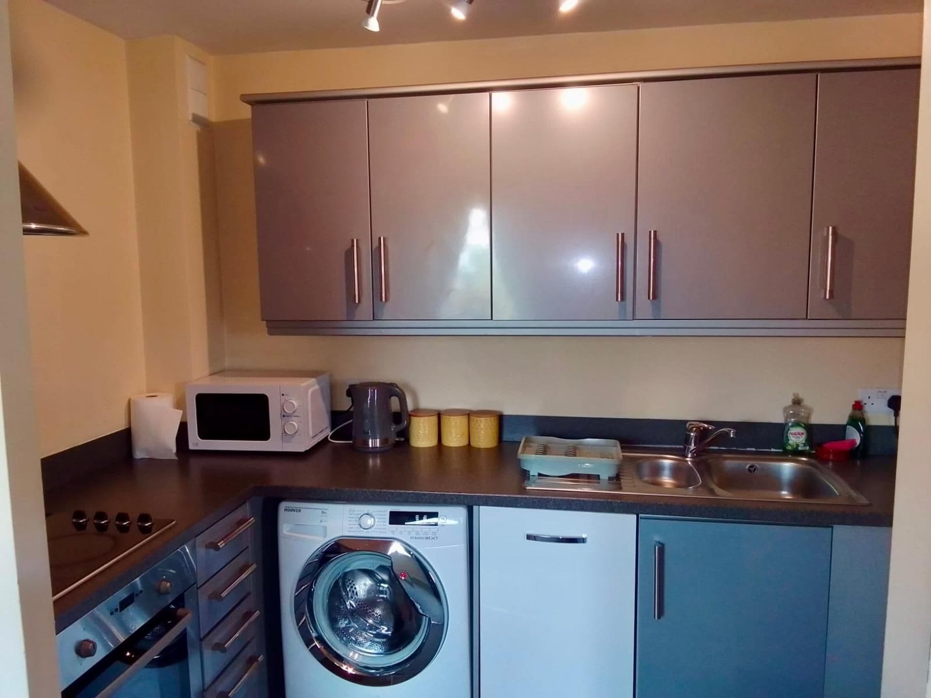 A compact kitchen with a washing machine, a microwave, and a sink.
