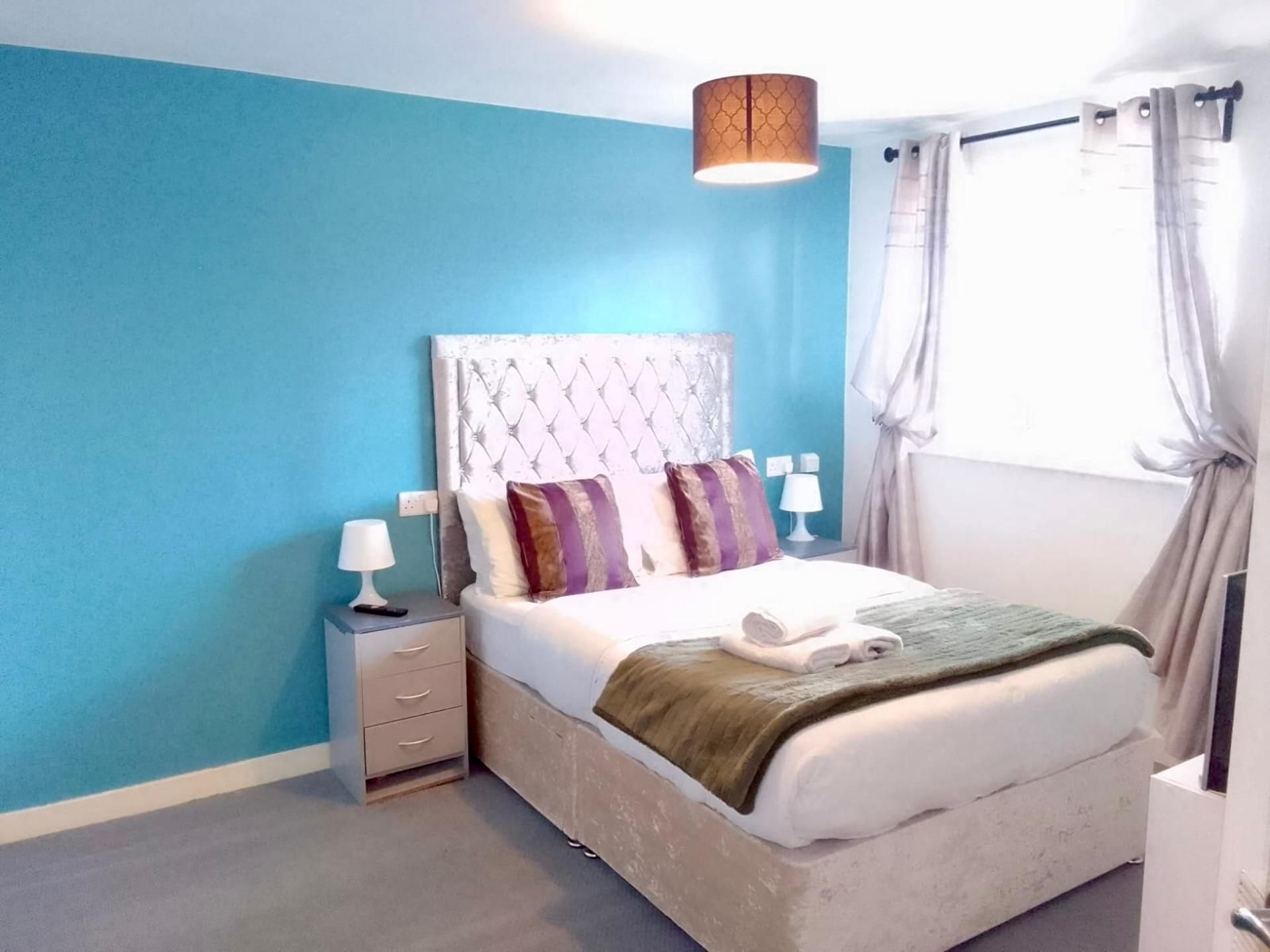 A bedroom with a bed, nightstands, a lamp, and a window with curtains.