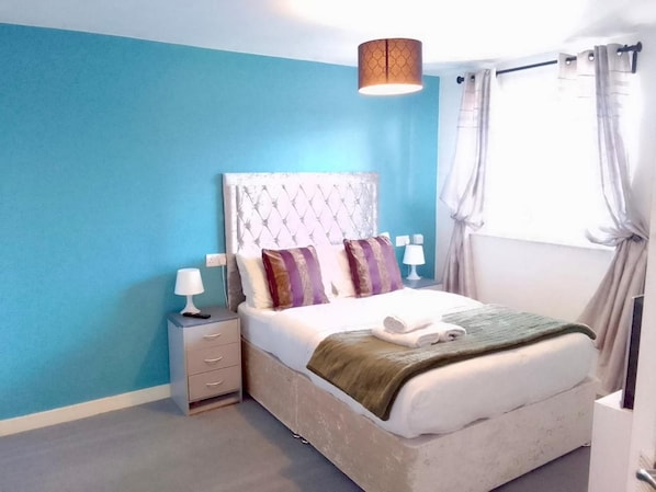 A bedroom with a bed, nightstands, a lamp, and a window with curtains. - Apartment Sleeps 4 With Wifi (Wolverhampton)