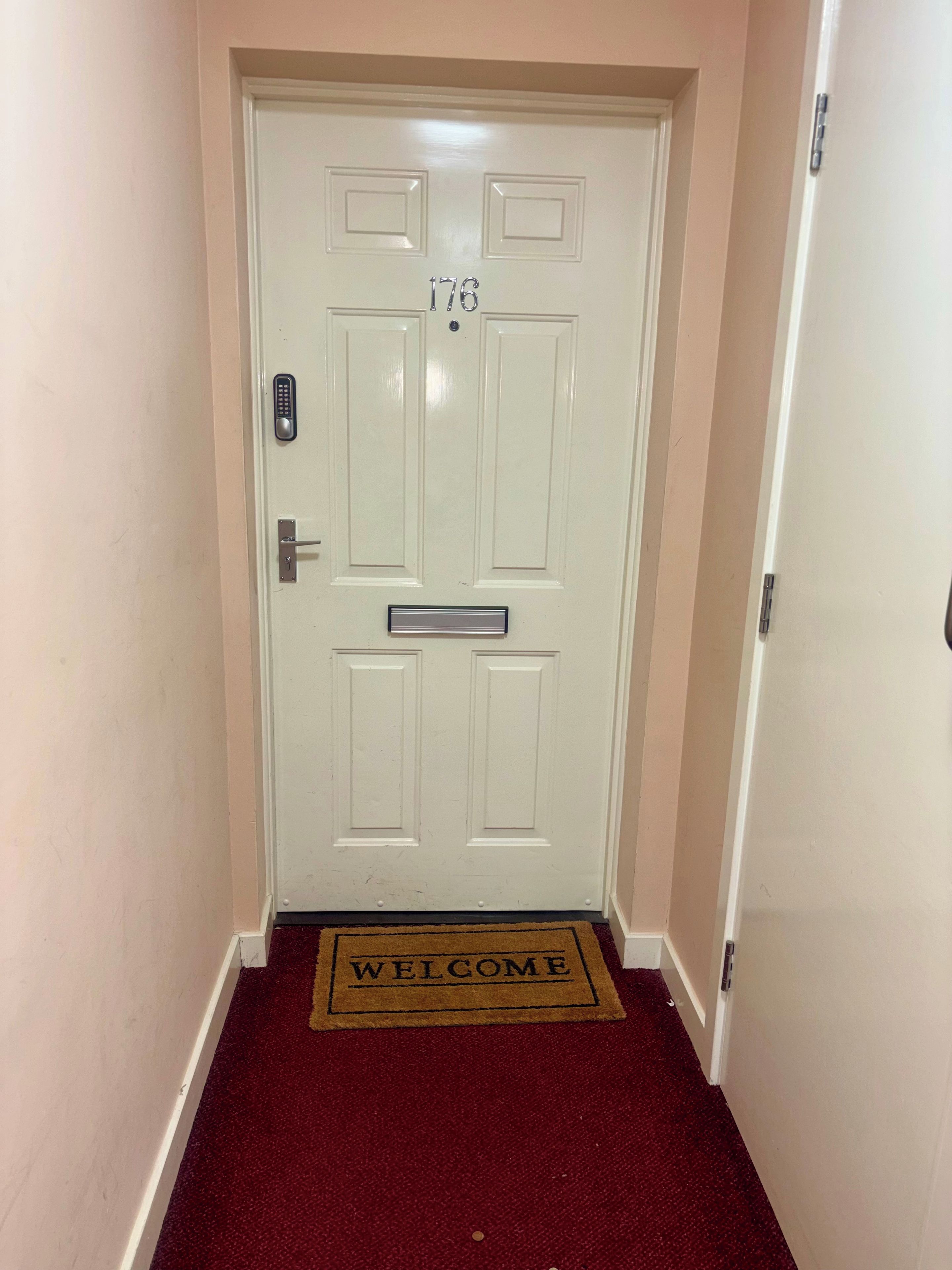 A white door with the number 176, a keypad lock, and a mail slot.