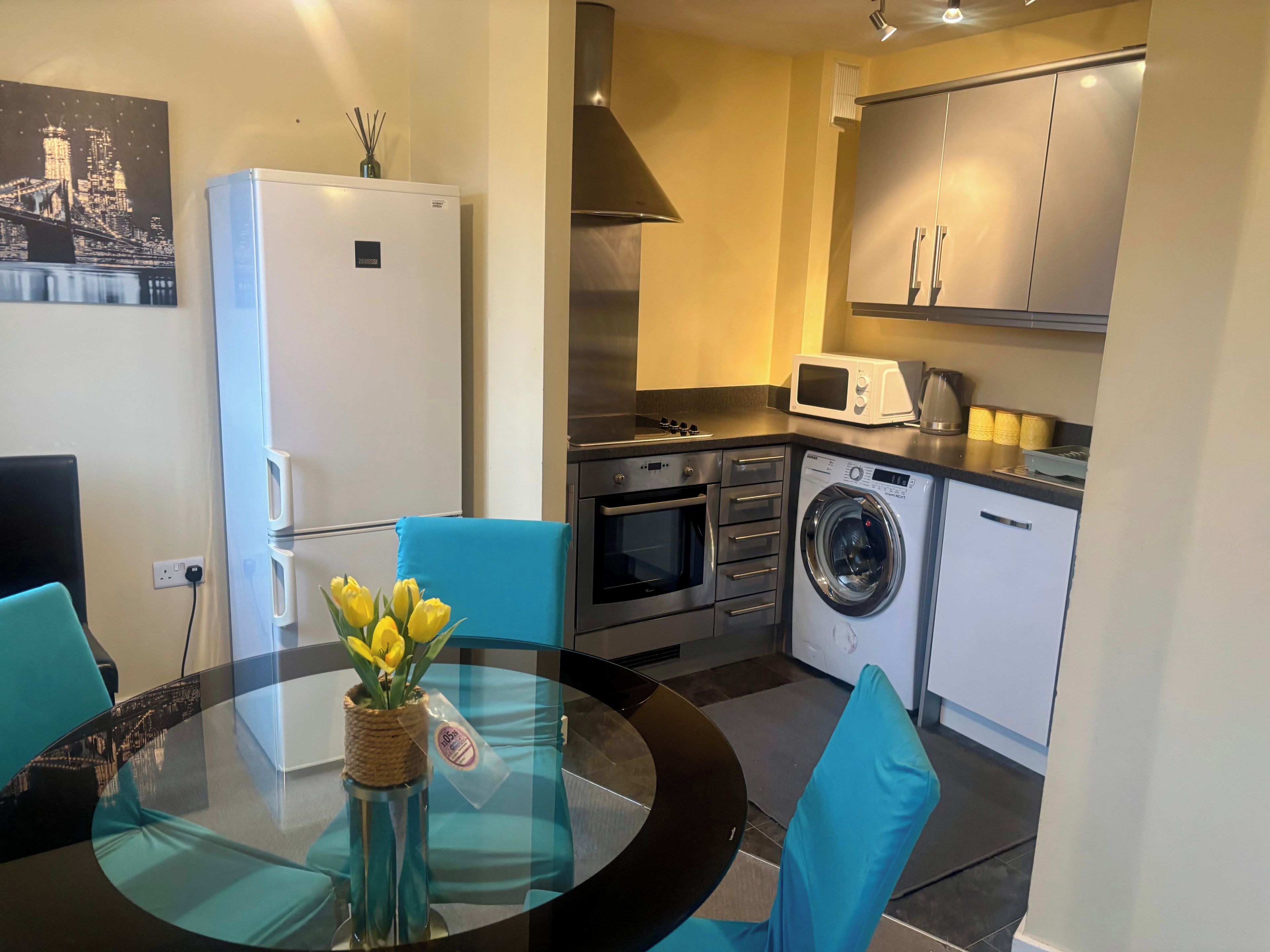 A compact kitchen with a refrigerator, microwave, oven, and washing machine.