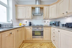 Une cuisine moderne avec des meubles en bois, une cuisinière en acier inoxydable et un four encastré.