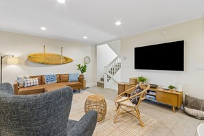 Ein modernes Wohnzimmer mit einer Couch, einem Sessel, einem Fernseher und einer Treppe.