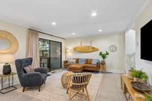 A modern living room with a sofa, armchair, and a large round mirror. - 3BR Sea Castles condo near Amelia Island beach with pool (Fernandina Beach)