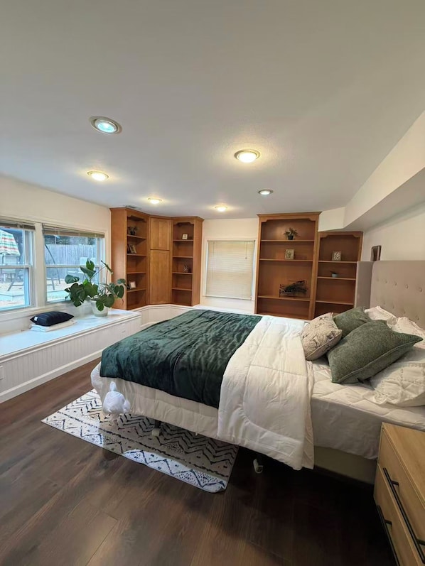 A bedroom with a bed, built-in shelving, a window, and a view of the outdoors.