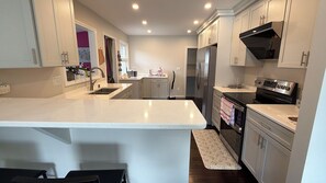 A modern kitchen with a central island, stainless steel appliances, and a walk-in pantry. - Spacious 4BR House in Blackstone, Near Brown, RISD & Miriam Hospital (Providence)