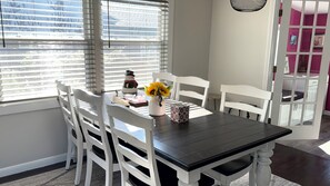 A dining area with a table and chairs, a vase with flowers, and a decorative item on the table. - Spacious 4-bedroom house in Blackstone Eastside Providence (Providence)
