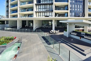 Ein modernes Gebäude mit mehreren Balkonen, Außenbereich mit Sitzgelegenheiten und einem Poolbereich.