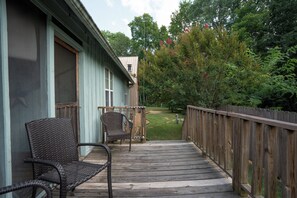 En træterrasse med to fletstole, et træhegn og et hus med lyseblå facade.