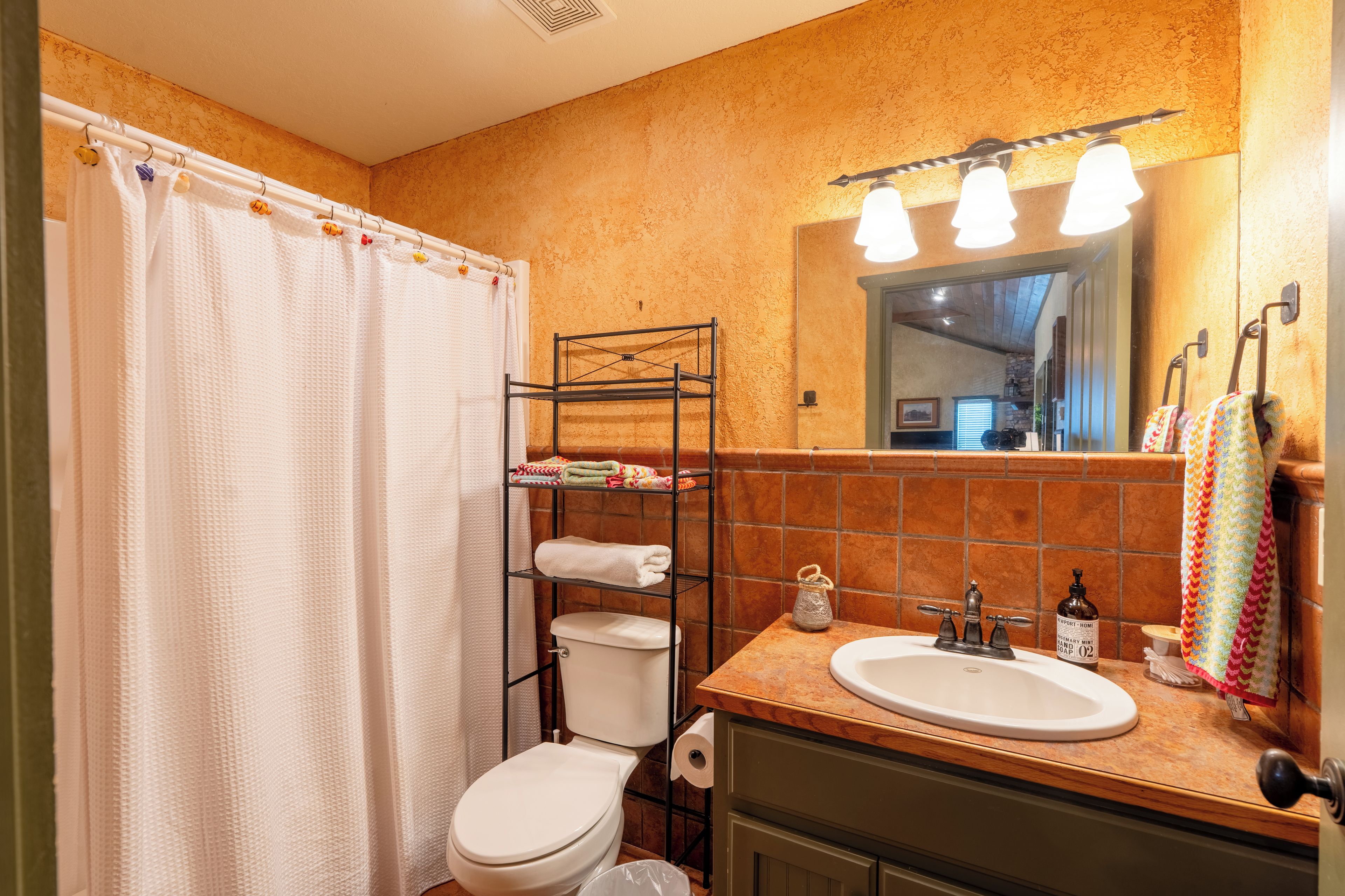 Een badkamer met douchegordijn, toilet, wastafel en handdoekhouder.