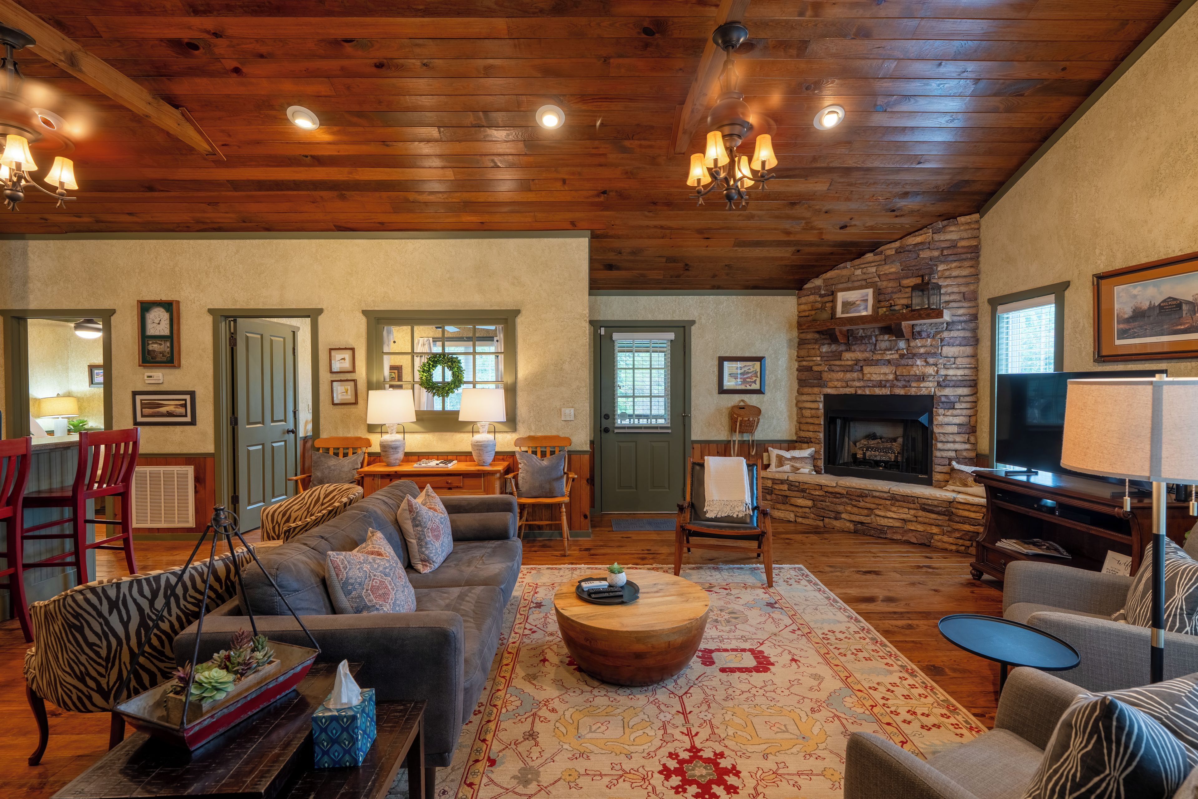A spacious living room with a fireplace, wooden ceiling, and a cozy seating area.