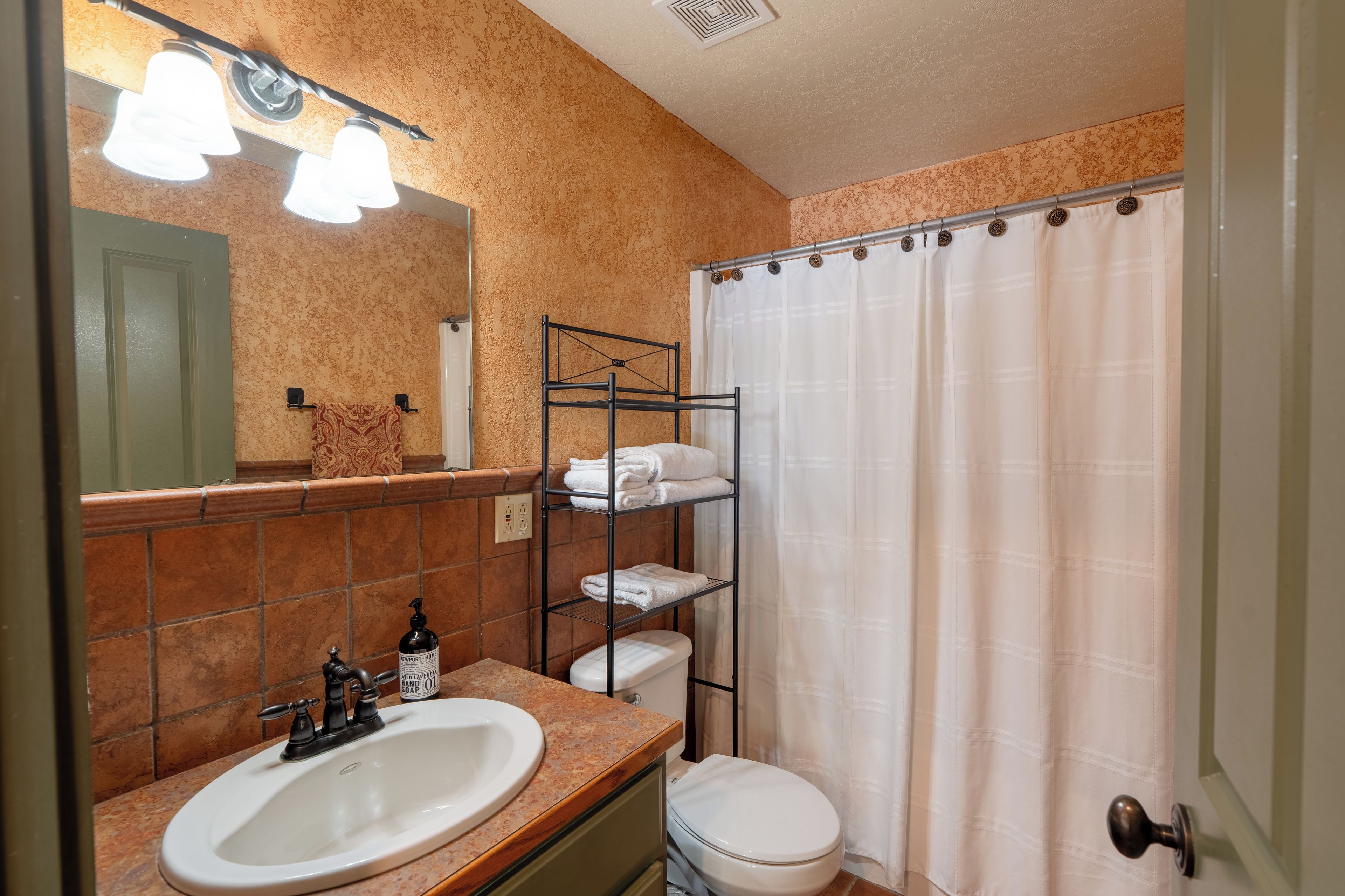 Un baño con lavamanos, inodoro y cortina de ducha.