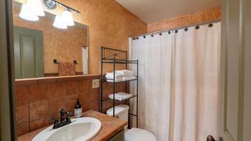 Un baño con lavamanos, inodoro y cortina de ducha.