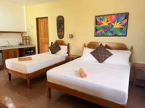 A hotel room with two single beds, a wooden headboard, a colorful abstract painting, a wooden door, and a small table with a cup. - Fantastic deluxe sea view villa with AC in beautiful El Nido (El Nido)