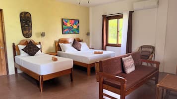 A hotel room with two beds, a wooden sofa, a ceiling fan, an air conditioning unit, and a window with curtains.
