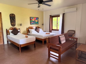 A hotel room with two beds, a wooden sofa, a ceiling fan, an air conditioning unit, and a window with curtains. - Fantastic deluxe sea view villa with AC in beautiful El Nido (El Nido)