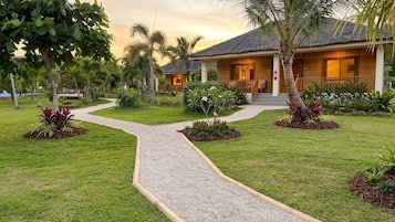 A resort with a paved pathway leading to a building with a thatched roof.