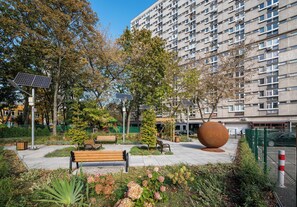 A park with benches, a large spherical sculpture, and solar panels. - Grzybowska Skyline Apartment (Wola)