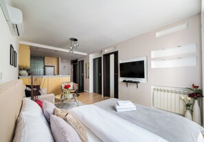 Ein modernes Hotelzimmer mit Bett, Fernseher, Küchenzeile und Esstisch.