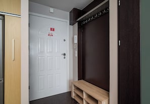 A hotel room with a white door, a wooden bench, and a dark wall. - Grzybowska Skyline Apartment (Wola)