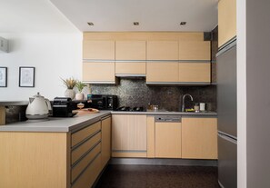 A modern kitchen with wooden cabinets, a built-in dishwasher, and a stainless steel refrigerator. - Grzybowska Skyline Apartment (Wola)