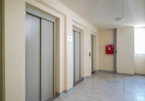 A hallway with doors, a fire alarm, and a sign indicating 'STRONA A'. - Grzybowska Skyline Apartment (Wola)