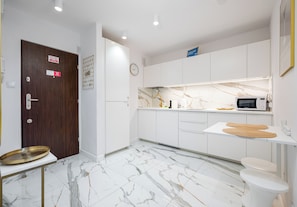 A modern kitchen with white cabinetry, a marble countertop, and a built-in microwave. - Park Mirowski Signature Apartment (Warszawa)