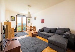 A modern living room with a grey sofa, wooden coffee table, and a TV stand. - Metro Racławicka Cosy Apartment (Warszawa)