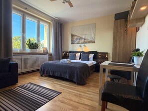 A modern hotel room with a large bed, a desk, a chair, and a window with curtains. - Dworcowa Old Town Studio (Wrocław)