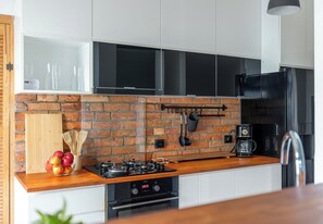 Eine moderne Küche mit Backstein-Spritzschutz, Edelstahlgeräten und Holzarbeitsplatten.