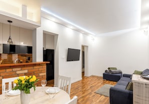 A modern apartment with a dining area, kitchen, living room, and a flat-screen TV mounted on the wall. - Małkowskiego Downtown Apartment (Szczecin)