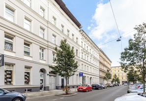 A street view with parked cars, a row of buildings with signage, and a clear sky. - Małkowskiego Downtown Apartment (Szczecin)