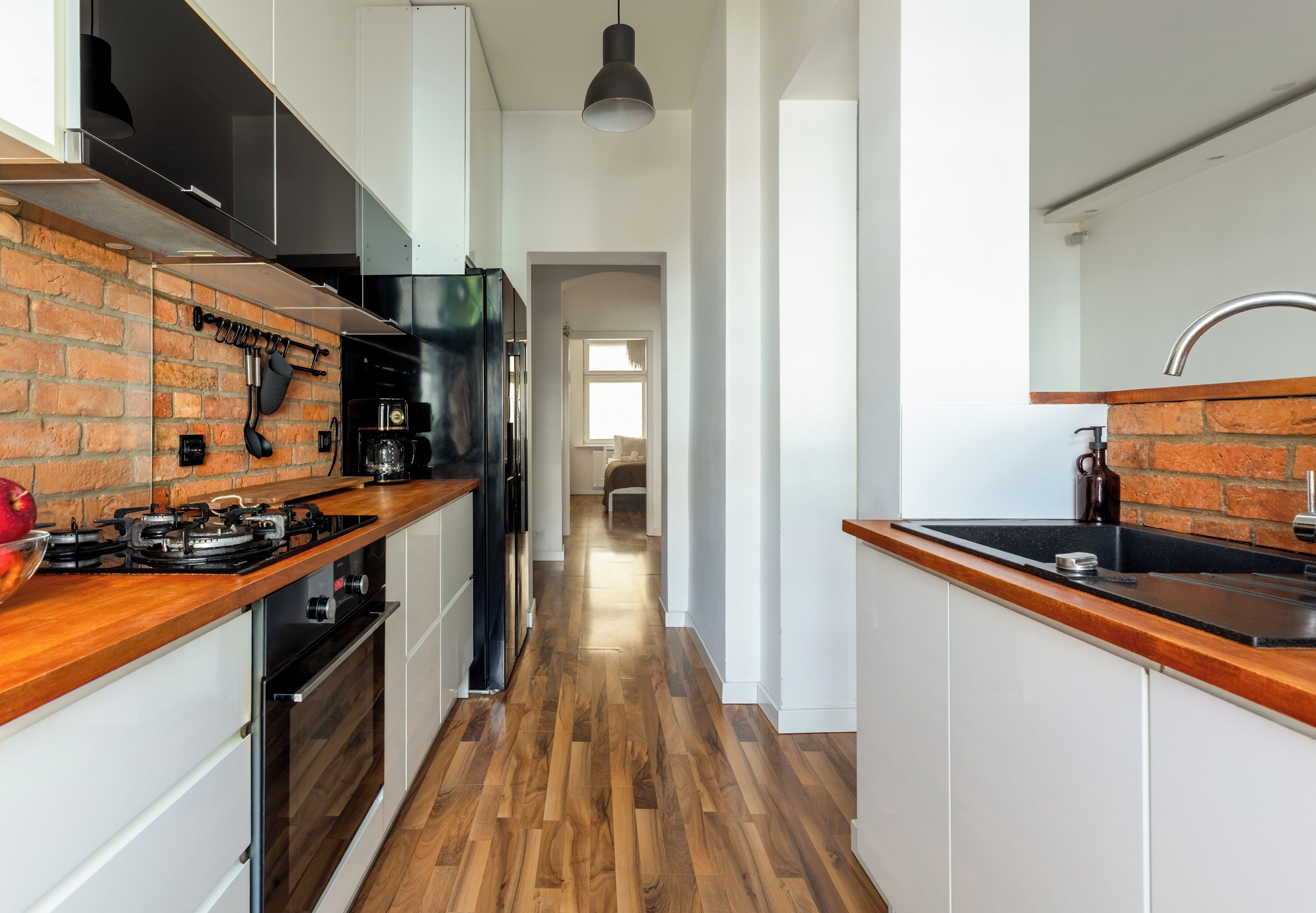 Eine moderne Küche mit Backsteinwand, Holz Arbeitsplatten und einer zentralen Kochinsel.