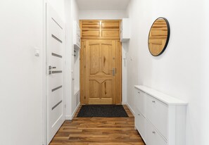 Un couloir avec une porte en bois, des armoires blanches et un tapis noir.