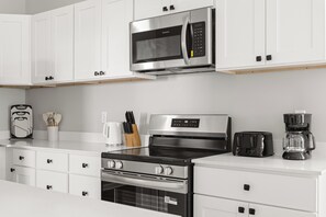 A modern kitchen with stainless steel appliances, white cabinetry, and a coffee maker. - Downtown Retreat Wi-Fi Unrestricted Parking (Indianapolis)
