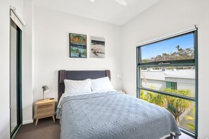 Ein Schlafzimmer mit einem Bett, einem Nachttisch, einer Lampe und zwei Bildern an der Wand.