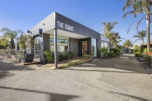 A modern building with a sign reading 'THE COAST'. - Upstairs Resort Apartment (Anglesea)