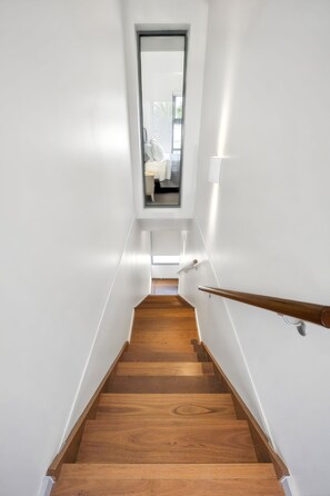 A staircase with wooden steps leading to a landing with a window. - Upstairs Resort Apartment (Anglesea)