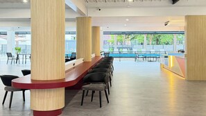 A spacious indoor area with a long reception desk, several chairs, and a view of an outdoor swimming pool. - B2 Muay Thai Pattaya Boutique & Budget Hotel (Pattaya)