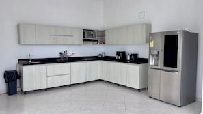 Una cocina moderna con un refrigerador de acero inoxidable, un microondas y una cafetera.