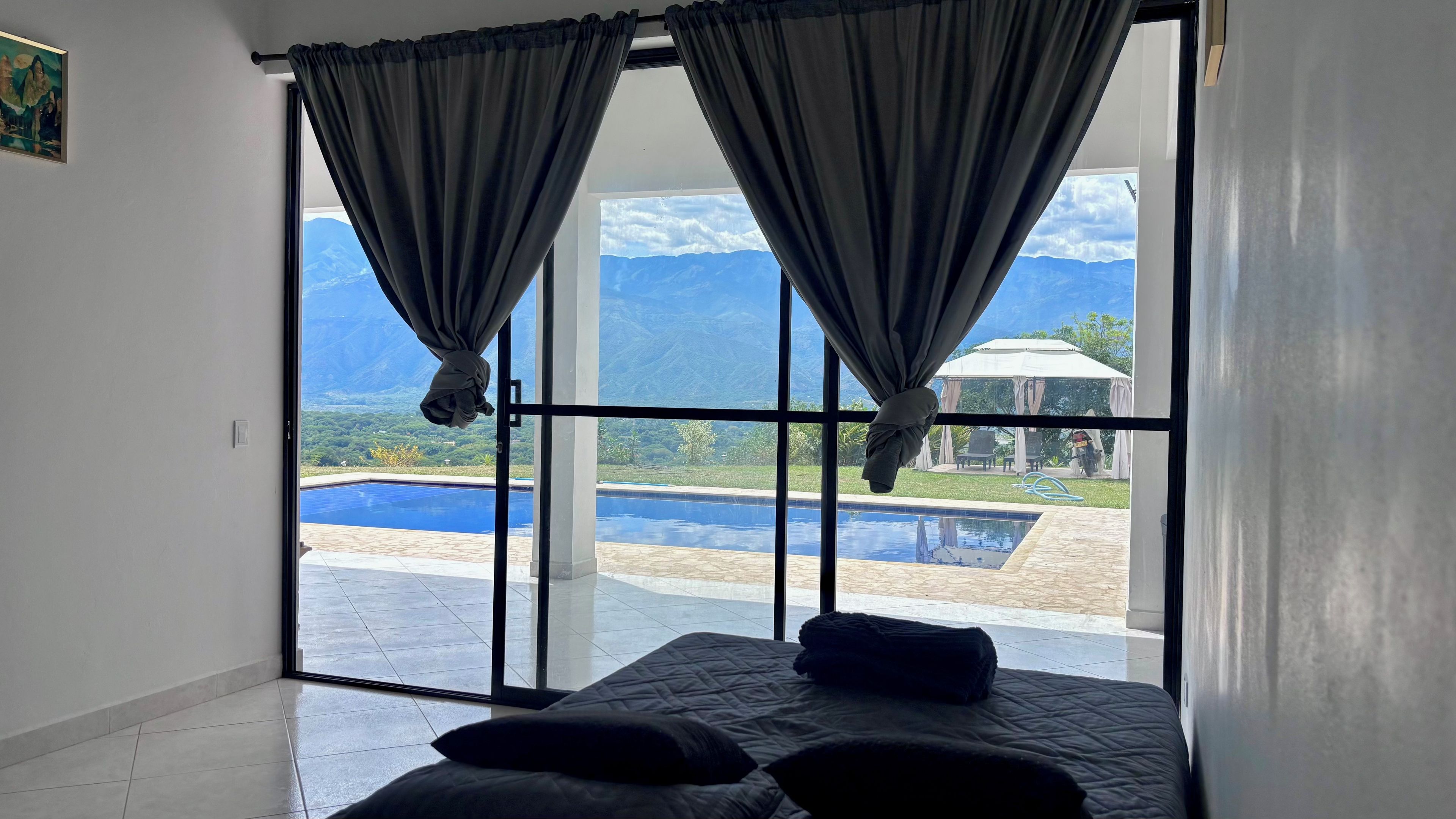 Una camera da letto con una grande finestra, un letto e vista su una piscina e montagne.
