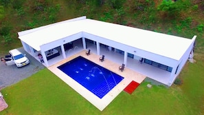 Un edificio moderno con piscina, terraza cubierta y fachada blanca.