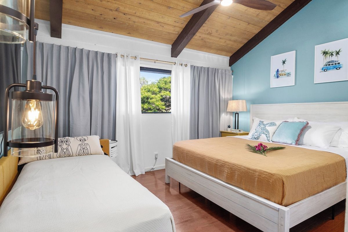 Une chambre d’hôtel avec un grand lit, une table de chevet, une lampe et une fenêtre avec des rideaux.