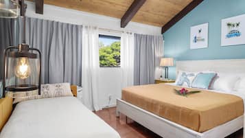 Une chambre d’hôtel avec un grand lit, une table de chevet, une lampe et une fenêtre avec des rideaux.