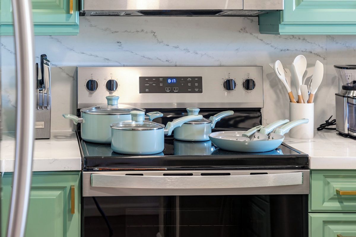 Une cuisine avec un four en acier inoxydable, une horloge numérique et des armoires de couleur turquoise.