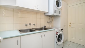 A kitchen with a double sink, a washing machine, and a door. - Cappa House, Kew by Property Mums (Kew)